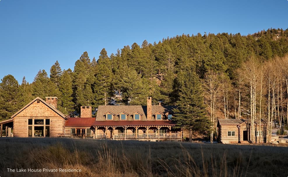 Rustic lodge-style residence surrounded by trees at the base of a forested hillside.