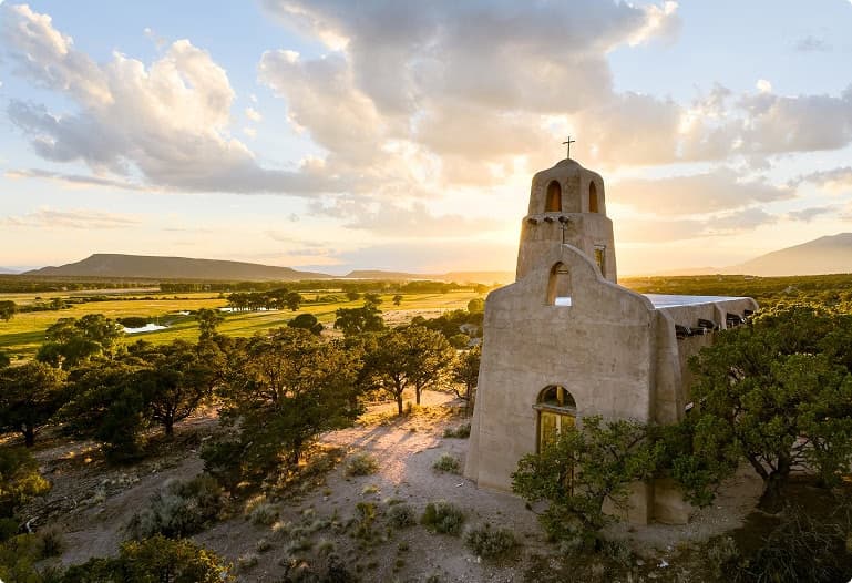 Historic adobe chapel overlooking expansive valley landscapes and mountain views during golden-hour sunset at Trinchera Reserve & Lodge.