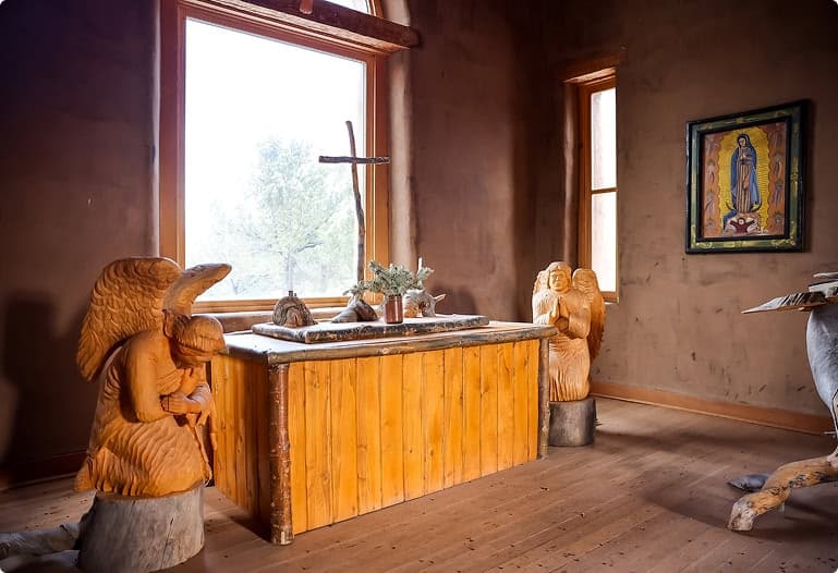 Handcrafted wooden chapel altar featuring angel carvings, religious artwork, and rustic Southwestern design elements inside the private chapel at Trinchera Reserve & Lodge.