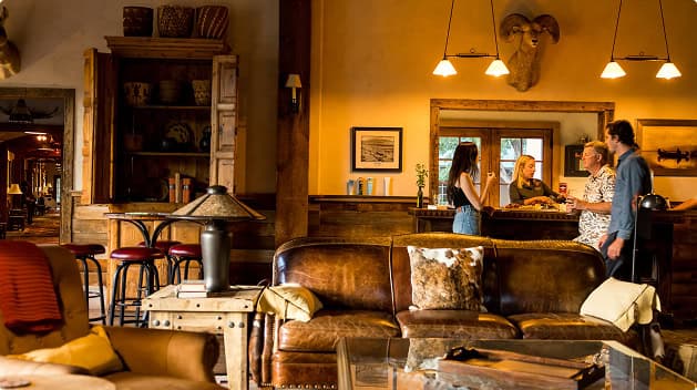 Guests socializing in a warm lodge great room featuring leather furnishings, rustic décor, and welcoming hospitality at Trinchera Reserve & Lodge.