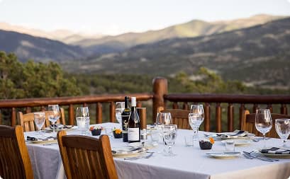 Elegant outdoor dining table set with wine and place settings overlooking sweeping mountain vistas at Trinchera Reserve & Lodge.