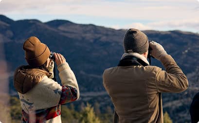 Guests using binoculars to observe wildlife and expansive mountain landscapes from a scenic overlook at Trinchera Reserve & Lodge.