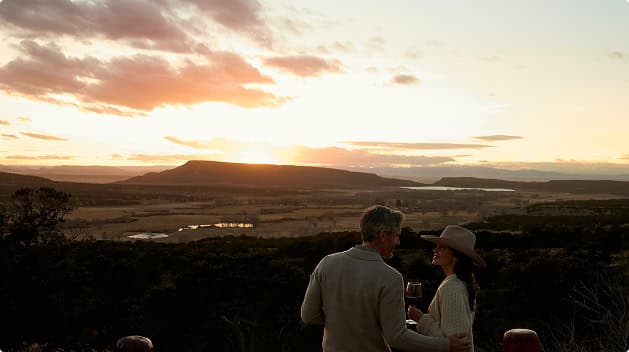 Couple enjoying wine and panoramic sunset views across valleys and mountain landscapes from a scenic overlook at Trinchera Reserve & Lodge.